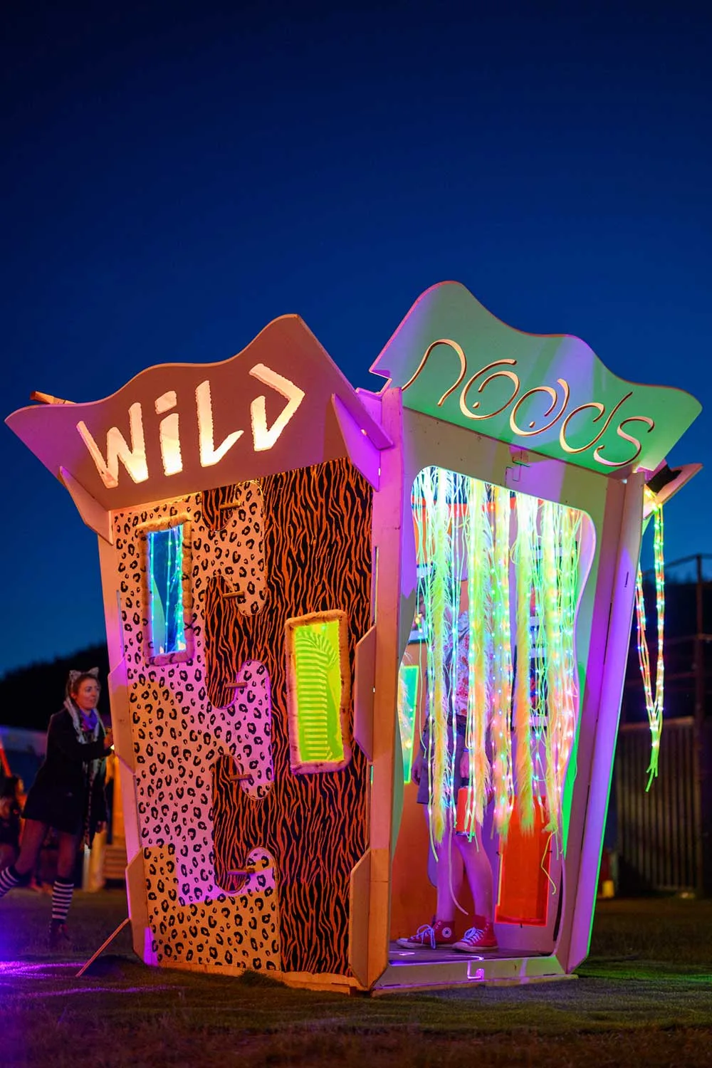 The Box at night — illuminated walk-in photo booth lit in neon