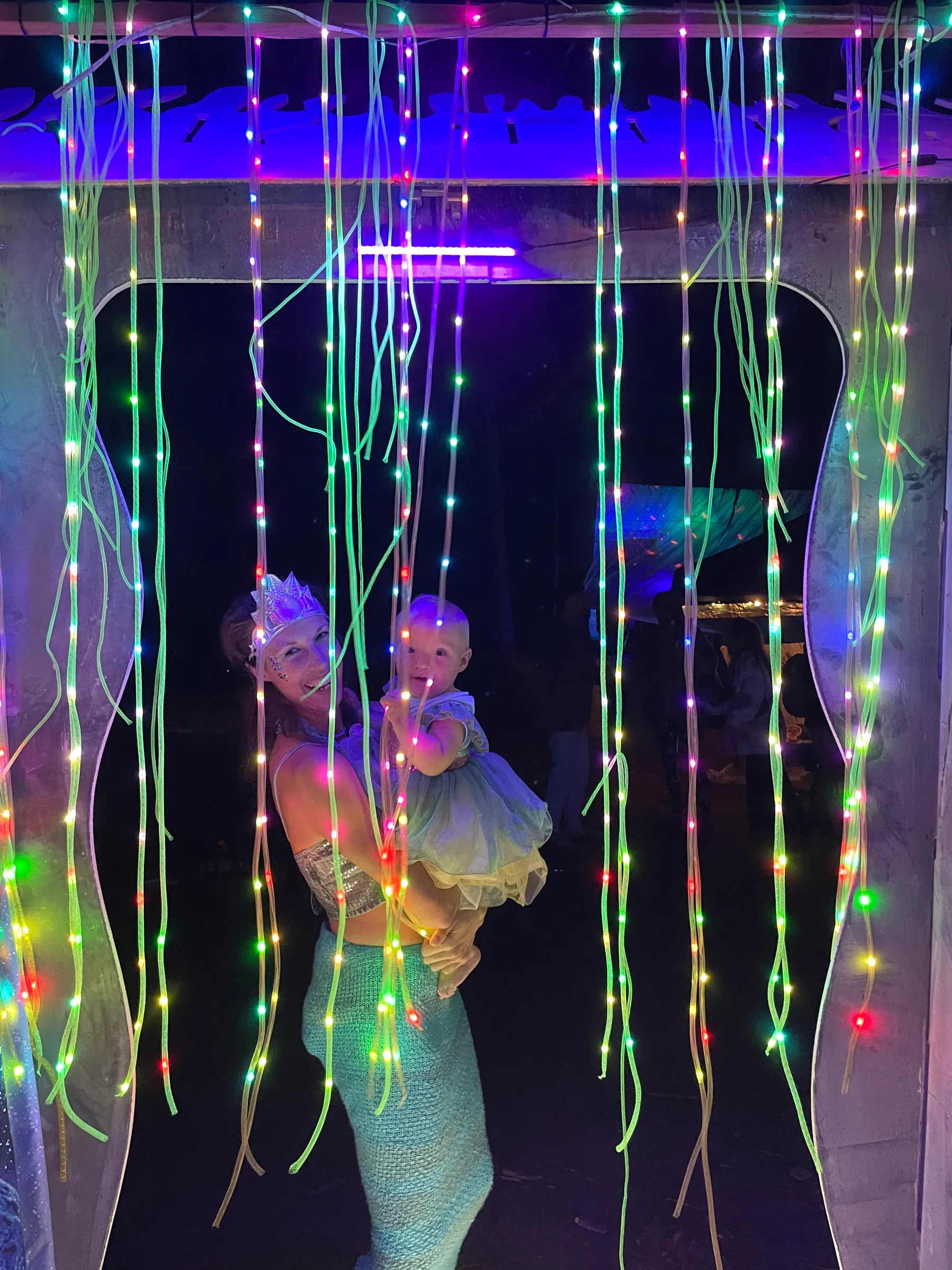 Inside the Noodle Box: a guest in costume poses behind the curtain of glowing noodle strands