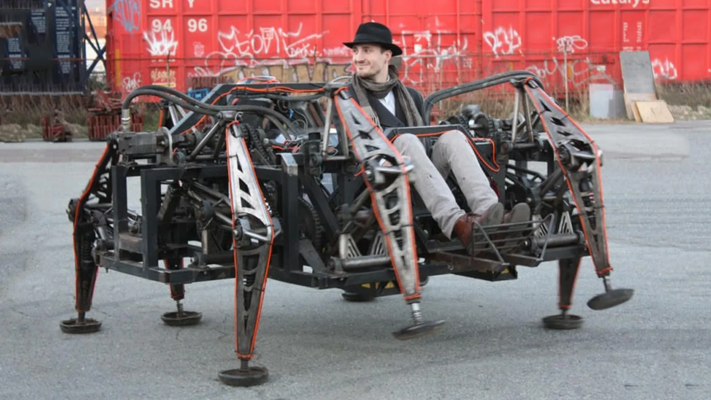The Mondo Spider, an eight-legged steel walking machine, with its rider seated in the middle in front of a graffitied rail car
