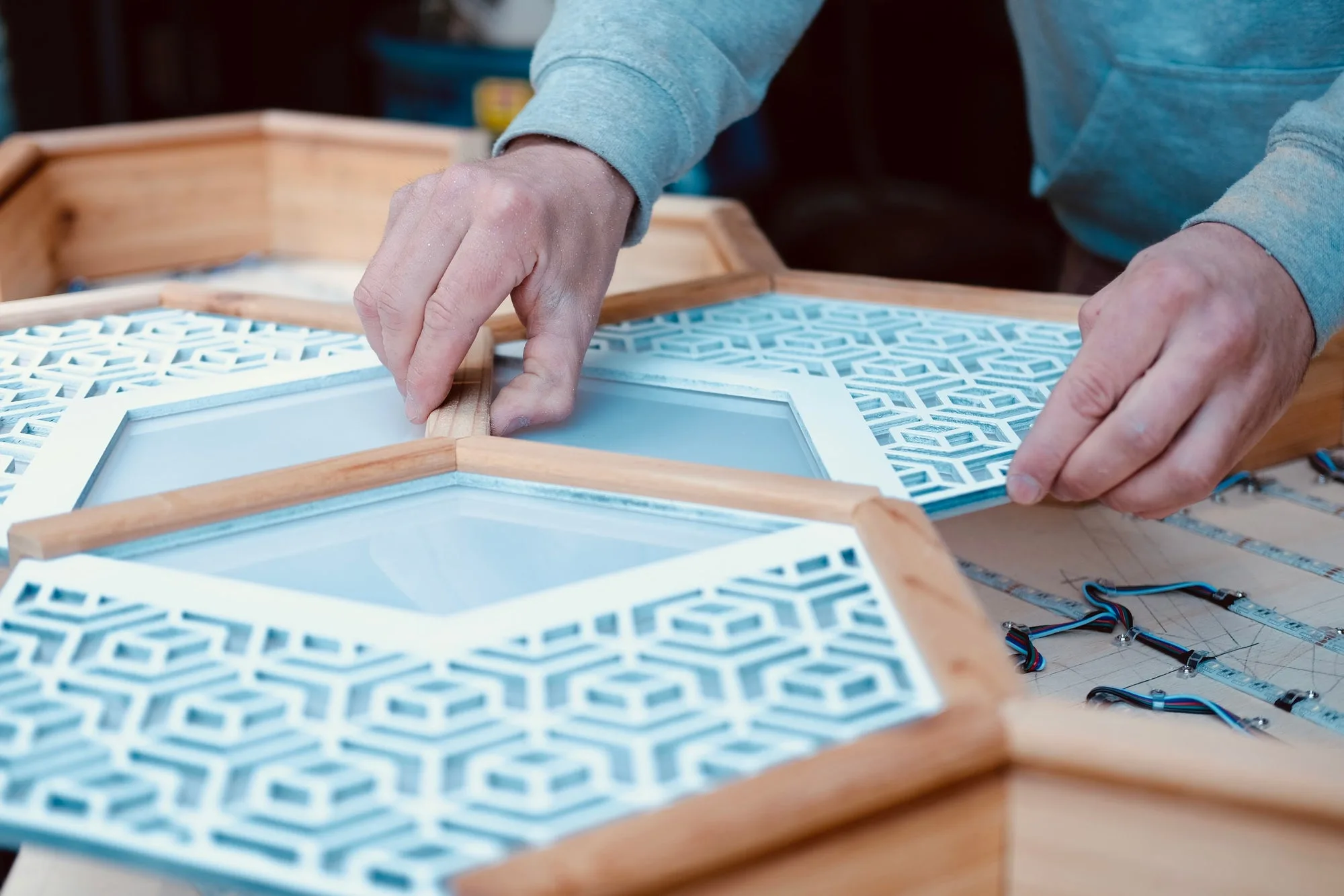 Close-up of hands fitting laser-cut hexagon faceplates into cedar frames during the build