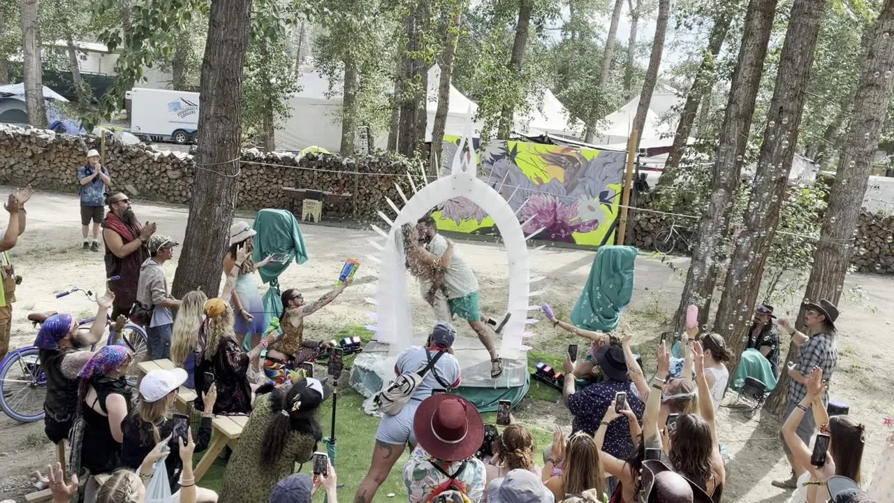 A festival crowd cheering a ceremony at the Arch in the Bass Coast forest