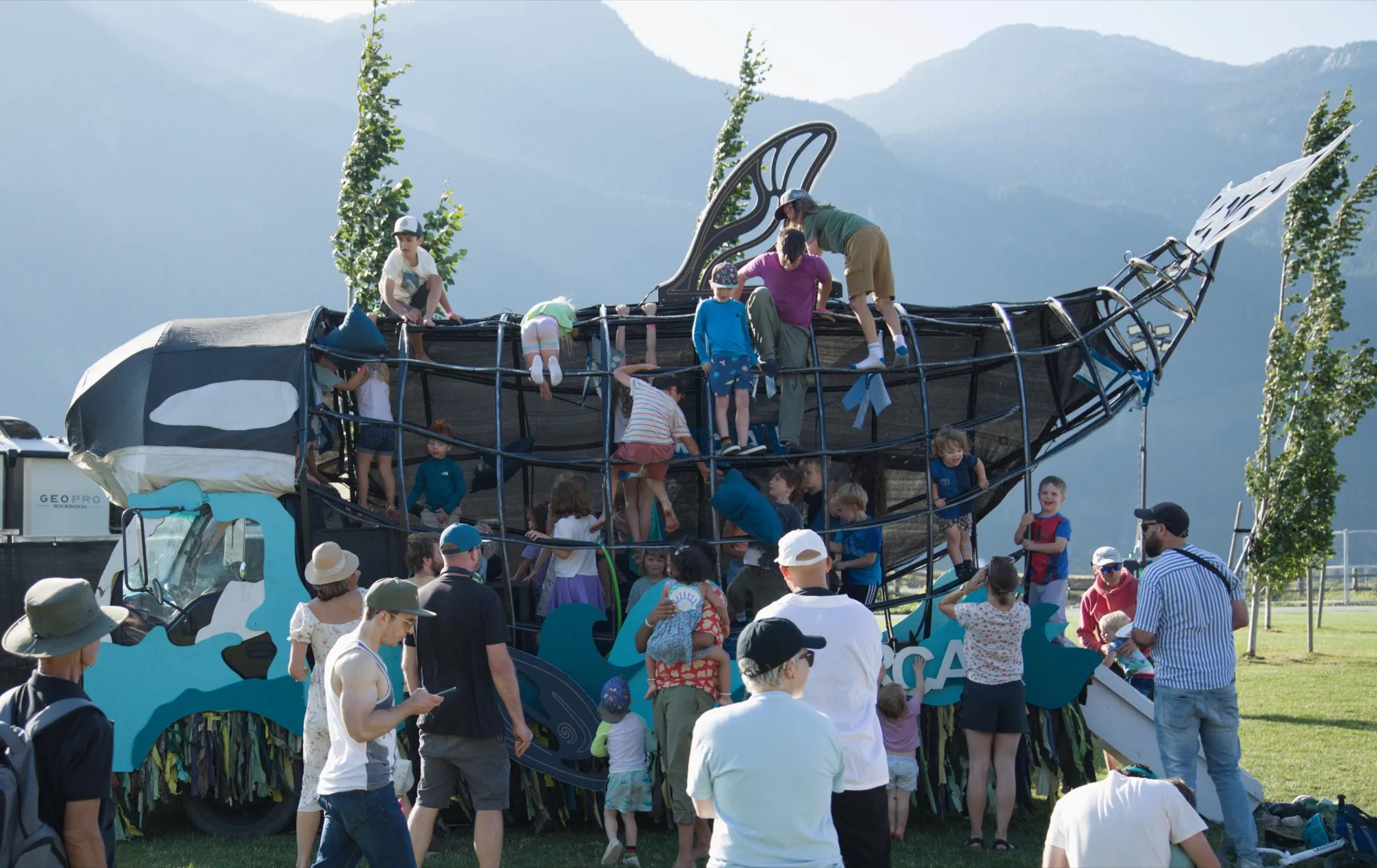 The Orcar in afternoon sun, kids climbing all over its steel ribs and dorsal fin, the Squamish mountains hazy behind
