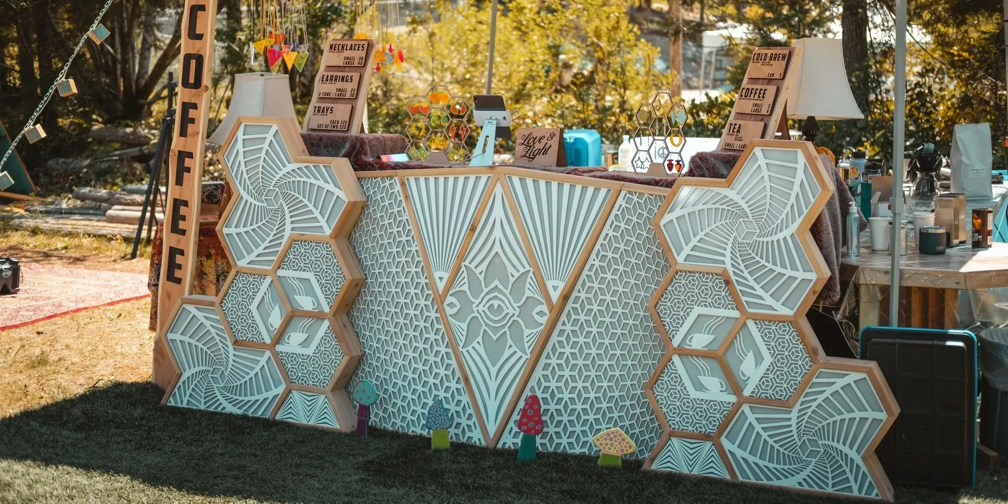 The Observer by day as a coffee bar front: laser-cut hexagon and spiral panels around a central eye, on grass